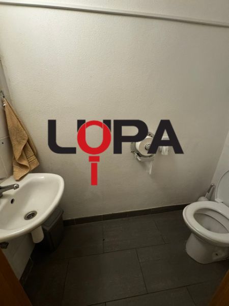 Toilette mit Waschbecken und Fliesen. Geschäftsräume mit einfacher Ausstattung.
