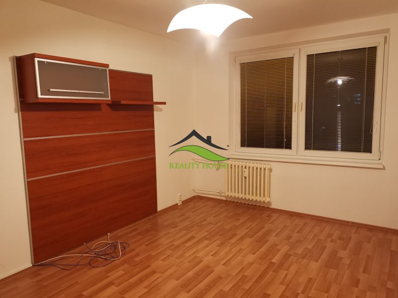 Ein Zimmer mit einem Boden in Holzoptik, weißen Wänden und einem Wandschrank in einer 3-Zimmer-Wohnung.