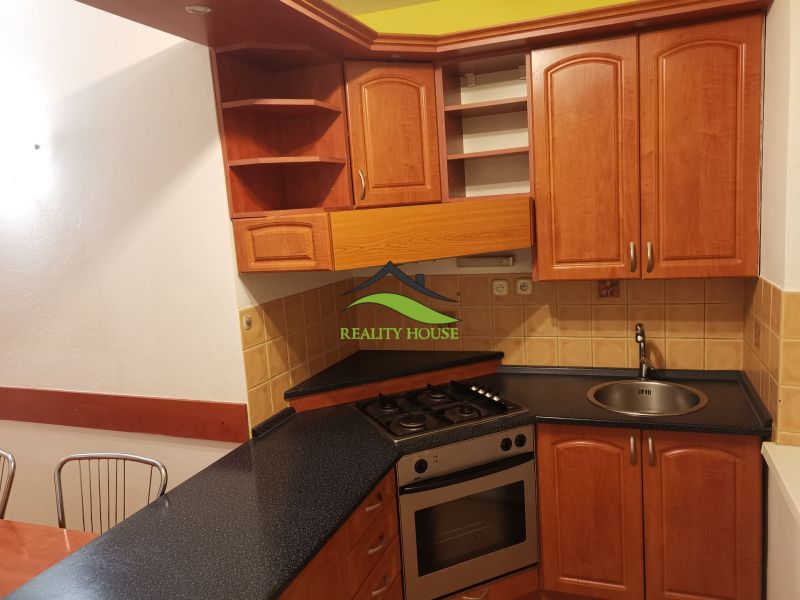 Küche in einer 3-Zimmer-Wohnung mit Holzschränken und Keramikfliesen.
