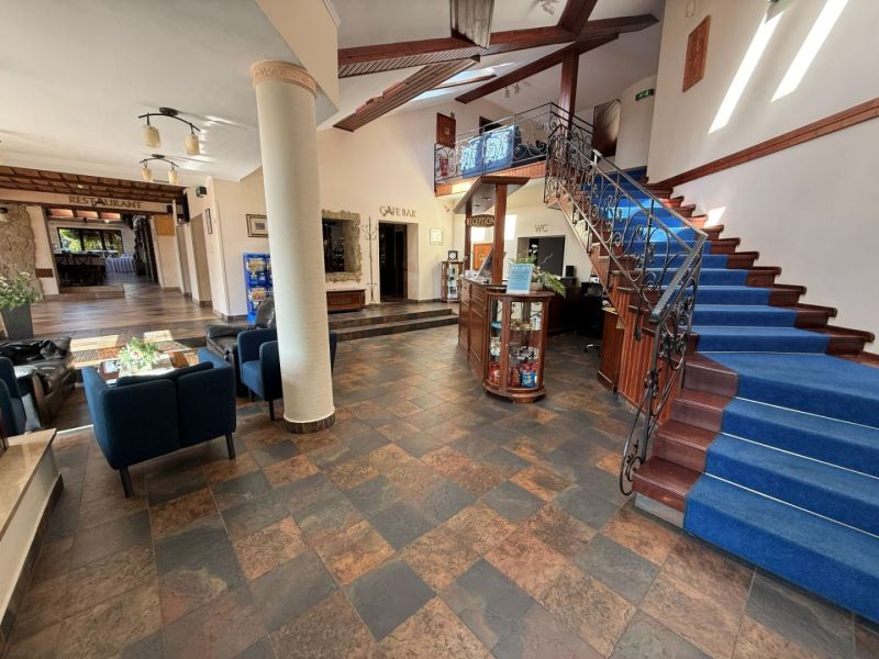 Hotelrezeption mit blauem Teppich auf der Treppe und Sesseln, Boden mit Holzdekor.