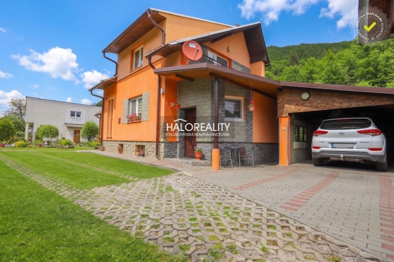 Einfamilienhaus in Dolná Mariková mit Garage, Rasen und Parkfläche vor dem Haus.