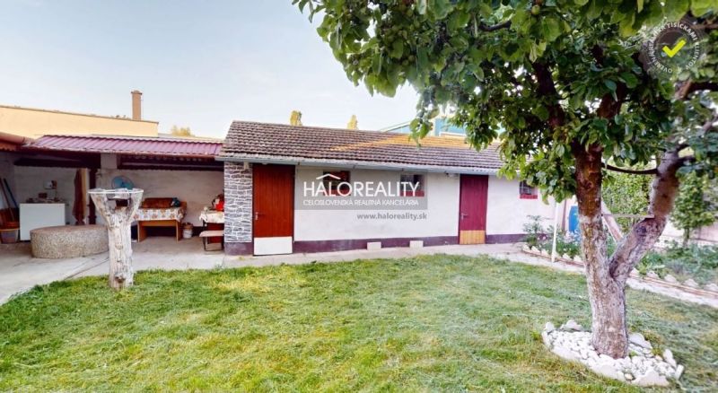 Garten bei einem Einfamilienhaus in Senica mit Rasen und Baum, Anbau hinten.