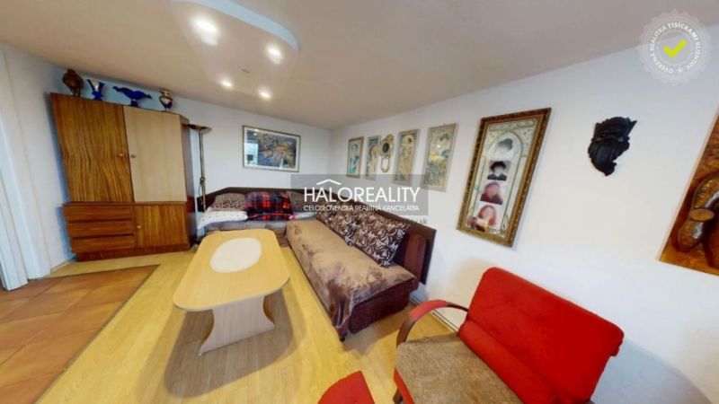 Wohnzimmer in einem Einfamilienhaus mit Sofa, Holzboden und Wandbildern.