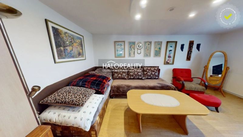 Wohnzimmer in einem Einfamilienhaus mit Sofa, Sesseln und Bildern an den Wänden, Boden mit Holzdekor.