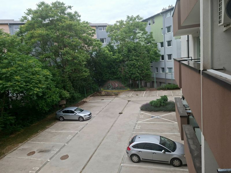Parkplatz in der Športová-Straße in Dunajská Lužná mit Autos und Grün im Hintergrund.