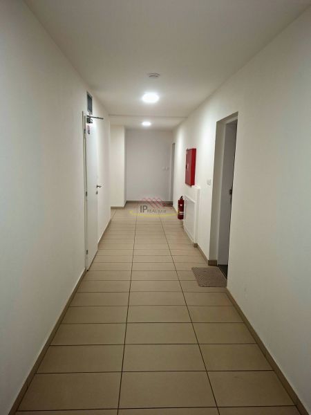 Chodba mit weißen Wänden, Fliesen und Notfallausrüstung im Einzimmerapartment.