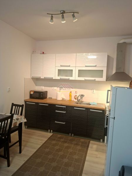 Küchenzeile in einem Einzimmerapartment mit Schränken, Esstisch, Boden mit Holzdekor.