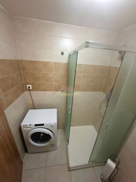 Badezimmer in einer Einzimmerwohnung mit Waschmaschine und Duschkabine.