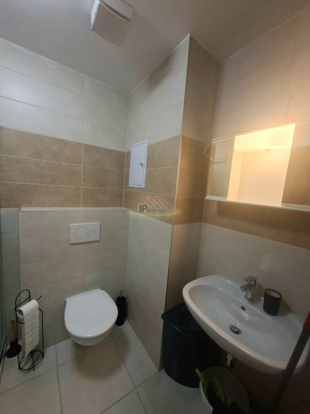 Badezimmer in einem Studio-Apartment mit Waschbecken, Toilette und gefliesten Wänden.