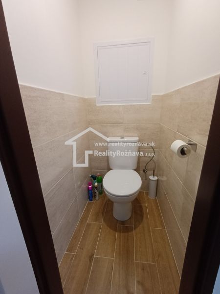Toilette mit Wand- und Bodenfliesen in Holzdekor in einer 3-Zimmer-Wohnung.