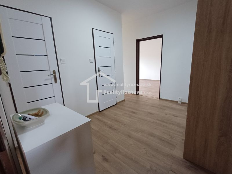 Innenraum einer 3-Zimmer-Wohnung mit weißen Türen und einem Boden in Holzoptik.