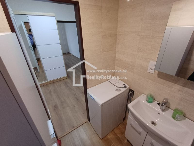 Badezimmer mit Spiegel und Waschmaschine in einer 3-Zimmer-Wohnung mit Holzboden.