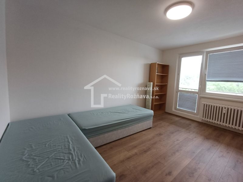 Ein Zimmer mit zwei Betten, einem Regal und einem Boden mit Holzdekor in einer 3-Zimmer-Wohnung.
