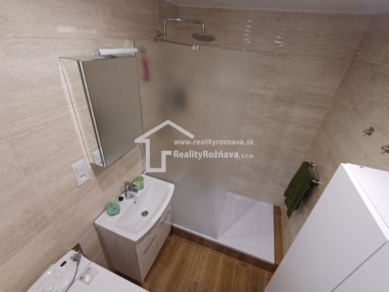 Badezimmer in einer 3-Zimmer-Wohnung mit Toilette, Duschkabine und Boden in Holzoptik.