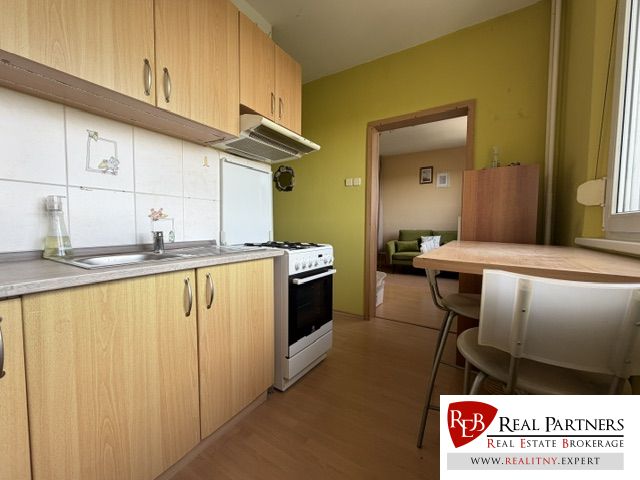 Küche in einer Einzimmerwohnung mit Holzboden, Esstisch und Ausstattung.