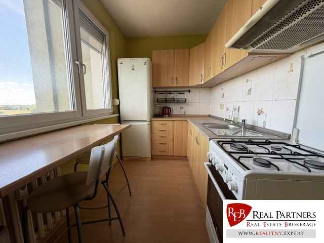 Küche in einer Einzimmerwohnung mit Holzboden und hellen Möbeln.