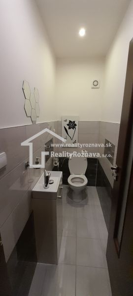 Badezimmer in einer 2-Zimmer-Wohnung mit Toilette, Waschbecken und hellen Fliesen.