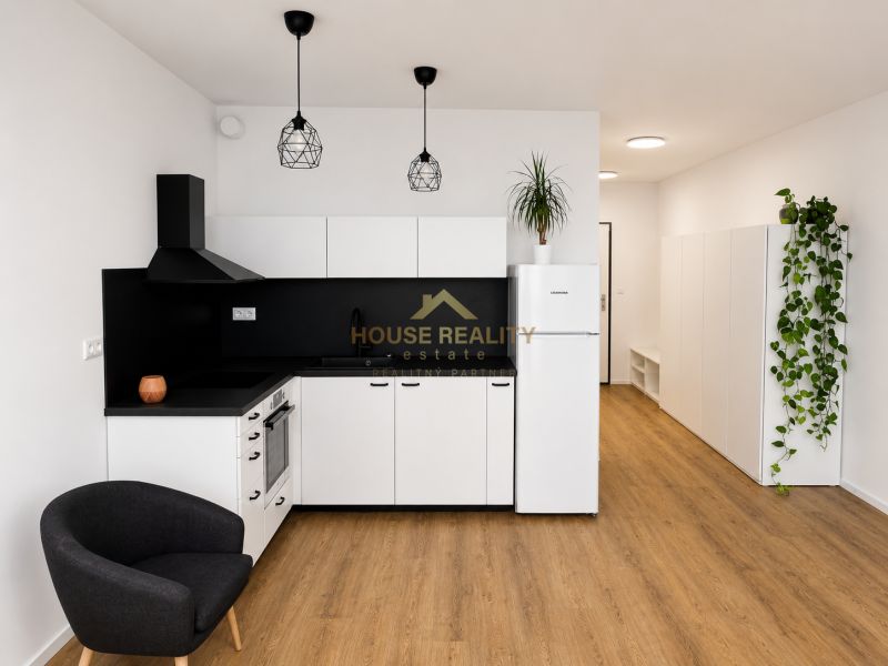Küche in einer Einzimmerwohnung mit weißen Schränken, schwarzen Details und einem Boden in Holzoptik.
