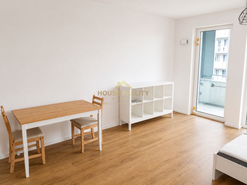 Wohnzimmer in einer Einzimmerwohnung mit Holzboden und Esstisch.