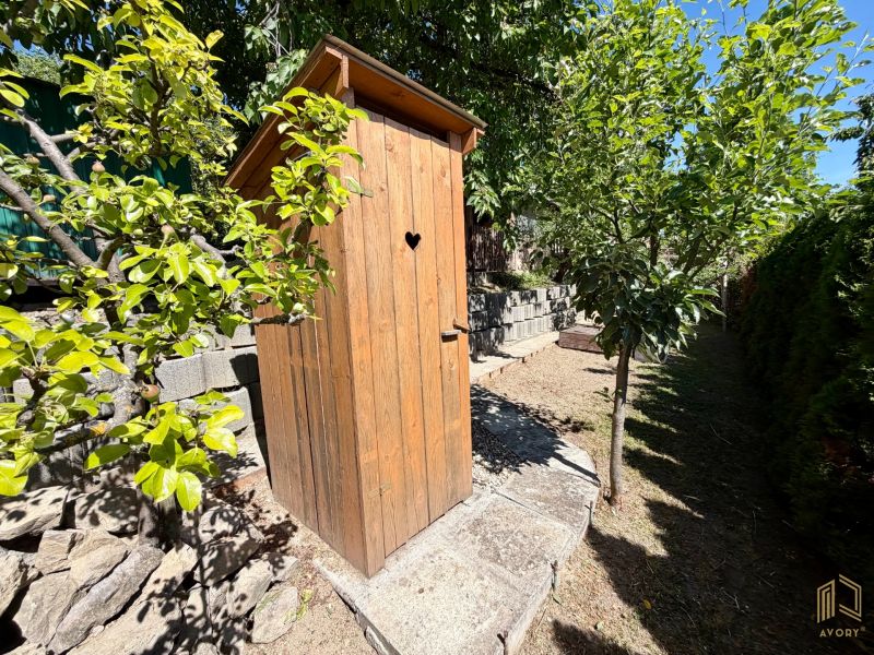 Holzlatrine bei der Hütte in Kunovo, Senica, umgeben von Grün und Bäumen.
