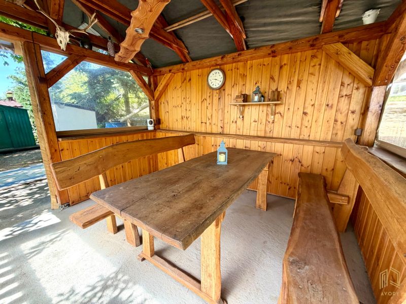 Eine Holzhütte mit einem massiven Tisch und Bänken bietet eine gemütliche Sitzgelegenheit.