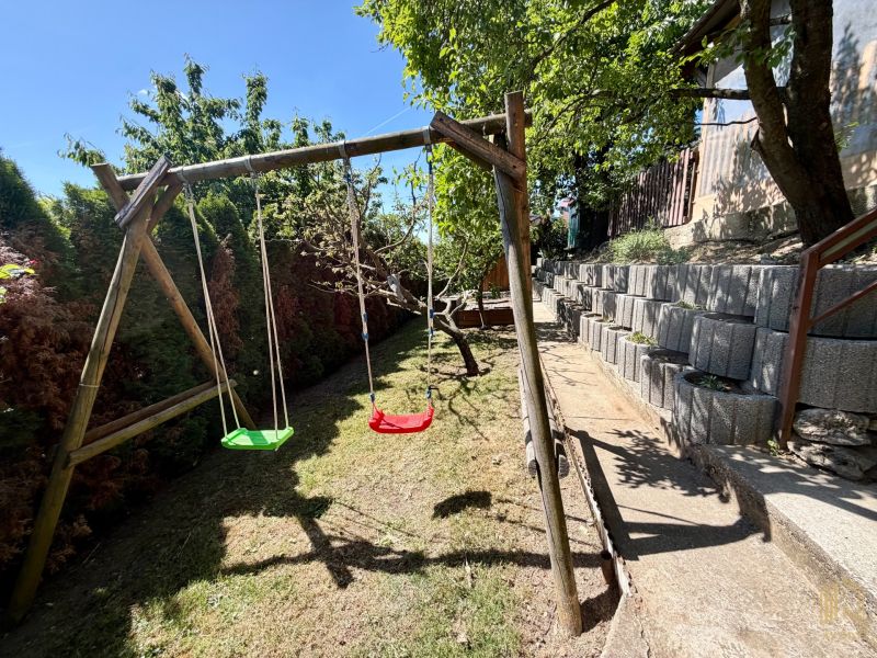 Holzschaukeln im Hof der Hütte in Kunov, Senica, mit terrassenförmiger Gartengestaltung.