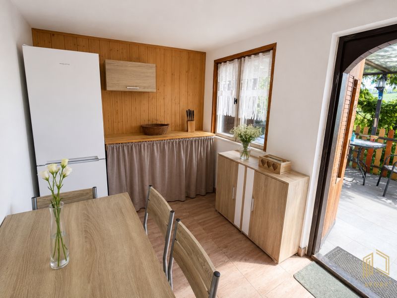 Küche in einer Hütte mit Holzboden, Tisch und weißen Blumen.