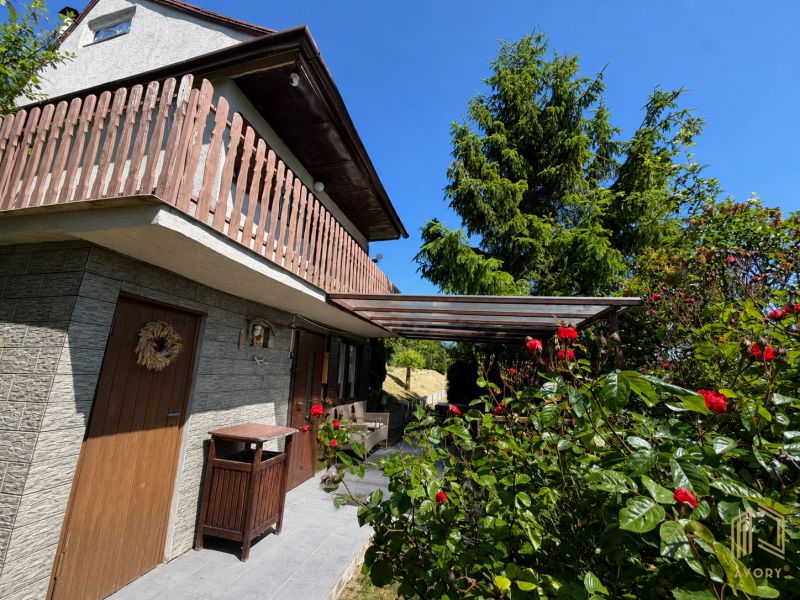 Eine Hütte in Kunov bei Senica, umgeben von Grün und Blumen mit Holzelementen.