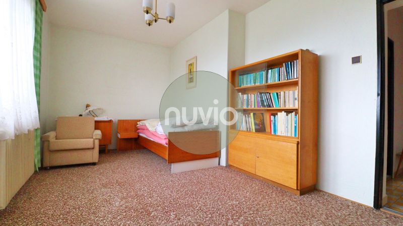 Ein Zimmer in einem Einfamilienhaus mit einem Stuhl, einem Bett, einem Regal und einem bunten Teppich.