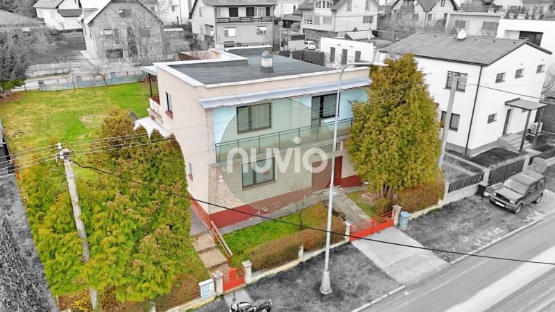 Ein zweistöckiges Einfamilienhaus in Martin mit Garten, umgeben von Bäumen und einem Zaun.