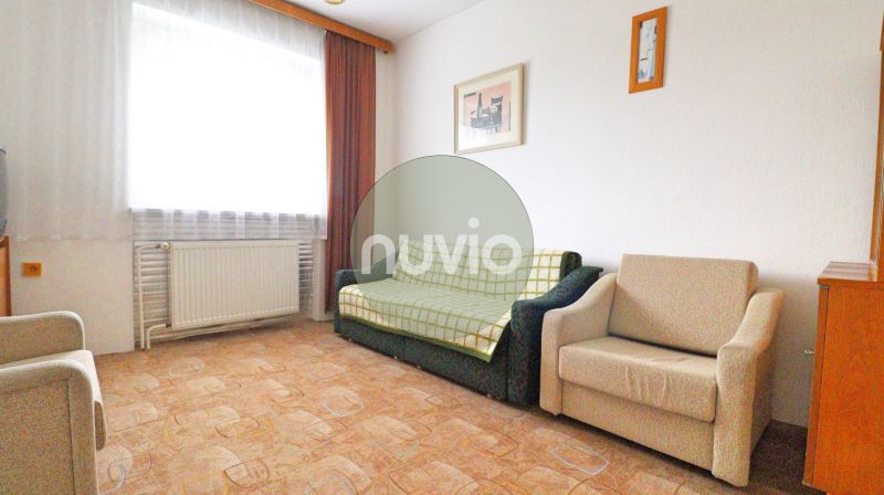 Wohnzimmer mit Sofa, Sessel, Bildern an der Wand, Holzboden.