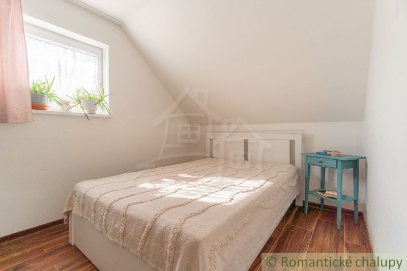 Schlafzimmer in einem Einfamilienhaus mit Bett, Nachttisch und Boden mit Holzdekor.