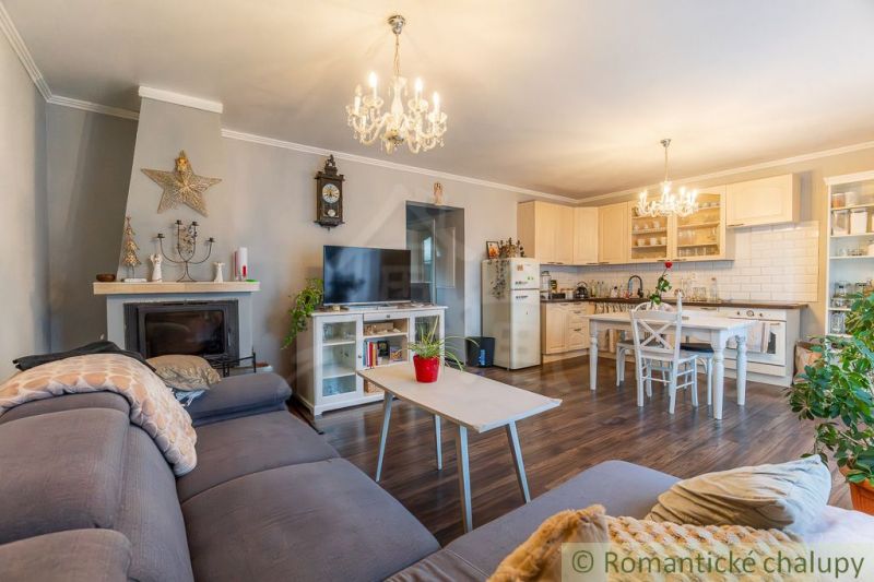 Wohnzimmer in einem Einfamilienhaus mit Kamin, Küche und Holzboden.