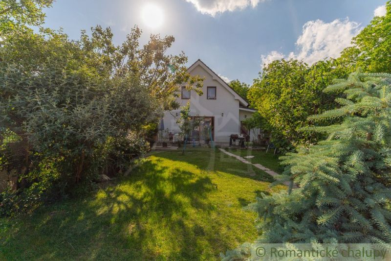 Ein Einfamilienhaus in Bernolákovo, umgeben von einem üppigen Garten auf einem sonnigen Grundstück.