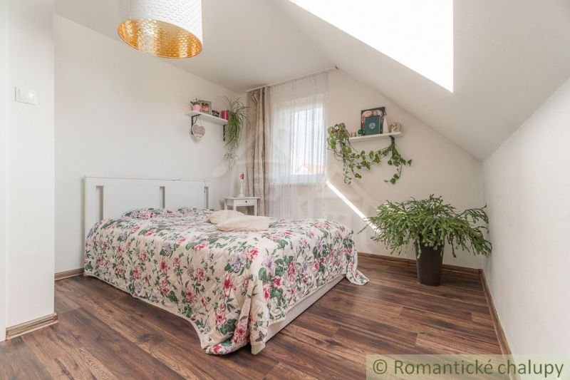 Ein helles Schlafzimmer in einem Einfamilienhaus mit Holzboden und Pflanzen.