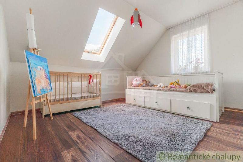 Kinderzimmer mit Bett, Holzelementen und Dachfenster in einem Einfamilienhaus.