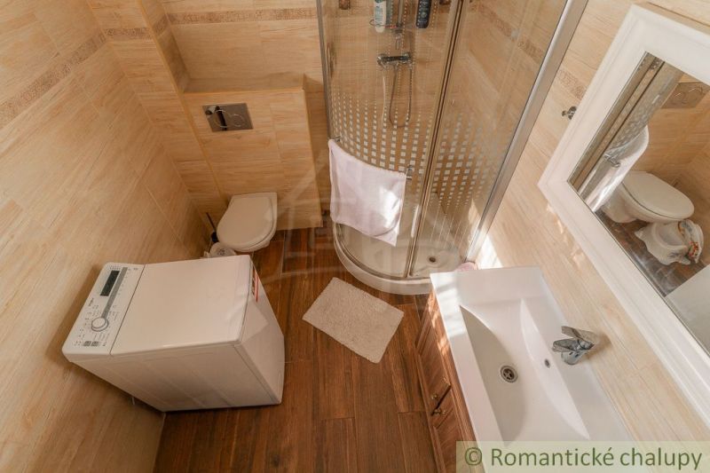 Badezimmer mit Waschmaschine, Dusche und Holzboden-Dekor in einem Einfamilienhaus.