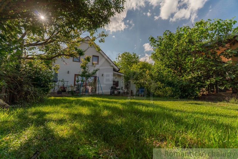 Ein Einfamilienhaus in Bernolákovo, umgeben von einem Garten mit Grünflächen und Bäumen.