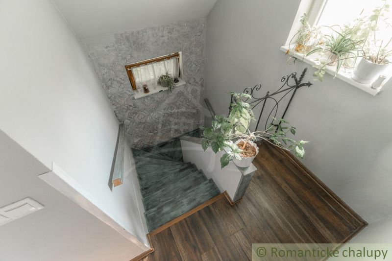 Eine Treppe im Einfamilienhaus mit Blumen und einem Boden in Holzoptik.