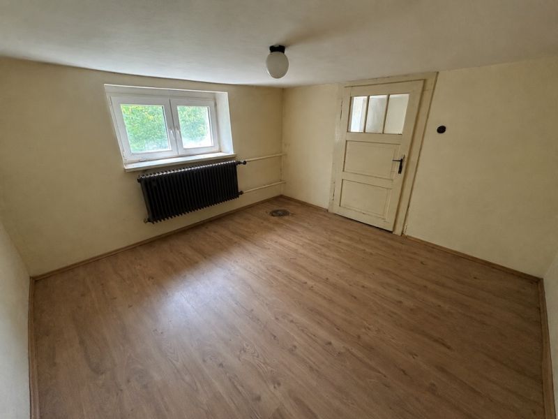 Ein Zimmer im Einfamilienhaus hat einen Boden mit Holzdekor und weiße Wände.