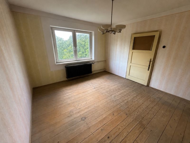 Ein Zimmer in einem Einfamilienhaus mit einem Holzboden und einem großen Fenster.