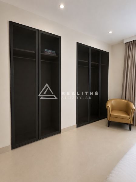 In der 4-Zimmer-Wohnung befinden sich ein schwarzer Schrank und ein beiger Sessel.