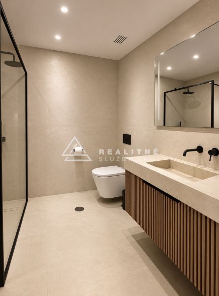 Badezimmer in einer 4-Zimmer-Wohnung mit Duschkabine und Holzdekor auf dem Schrank.