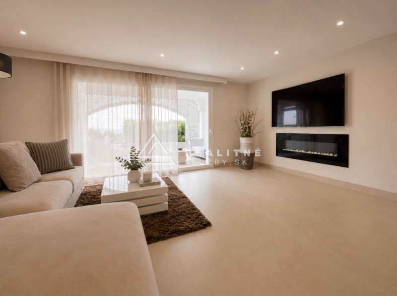 Wohnzimmer einer 4-Zimmer-Wohnung mit einem bequemen Sofa und einem Fernseher an der Wand.