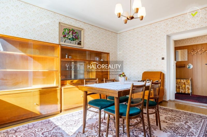 Esszimmer in einem Einfamilienhaus mit Holzmöbeln, Tapeten und Licht von einem Kronleuchter.