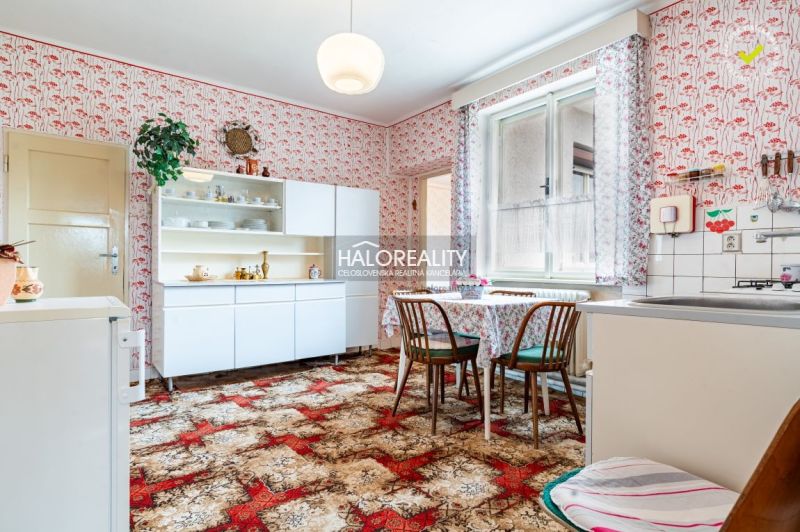 Küche in einem Einfamilienhaus mit retro gemusterten Tapeten, Möbeln und Esstisch.