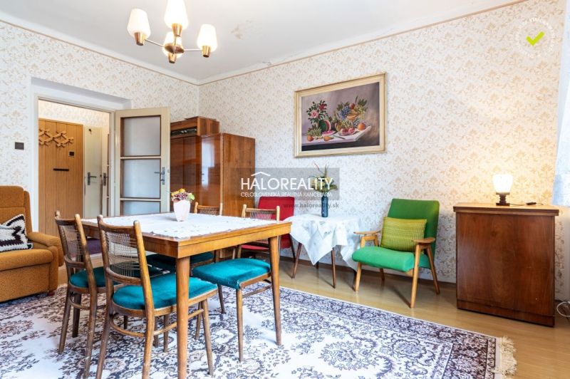 Innenraum eines Einfamilienhauses mit Retro-Möbeln, gemusterten Tapeten und einem Boden mit Holzdekor.