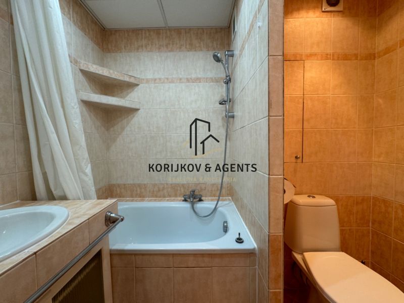 Badezimmer mit Badewanne und Toilette in einer 2-Zimmer-Wohnung mit Fliesen in Beigetönen.