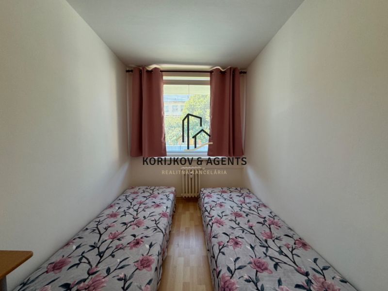 Gemütliches Schlafzimmer in einer 2-Zimmer-Wohnung mit Holzboden und Blumenbettwäsche.