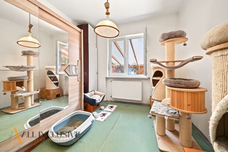 Ein Zimmer in einem Einfamilienhaus mit einem Katzenbaum, einem Spiegelschrank und einem Boden mit Holzdekor.